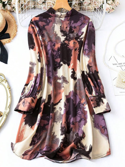 Burning Bones GEO Printed Tank Midi Dress featuring abstract watercolor pattern in purple, coral, and cream tones, with long bell sleeves, fitted waist, and flowing midi-length skirt. Elegant casual dress displayed on wooden hanger against floral background.