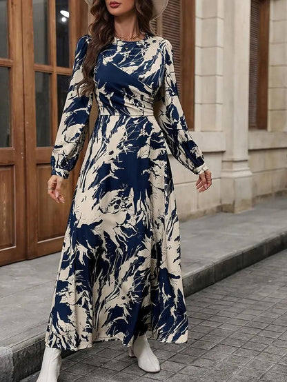 Burning Bones Allover Print Crew Neck Dress featuring elegant navy and cream abstract floral pattern, long bishop sleeves, fitted waist, and flowing ankle-length silhouette. Maxi dress showcased in outdoor setting with classic architectural backdrop.